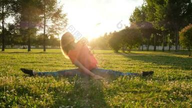 在一个城市公园里, 女子体操运动员坐在草地上, 做伸展运动